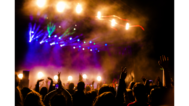 Picture of a lot of people enjoying night perfomance, large unrecognizable crowd dancing with raised up hands and mobile phones on concert. nightlife