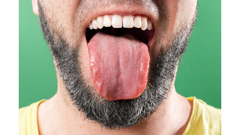 Caucasian bearded man sticks out his tongue. Close-up