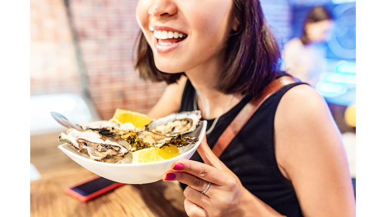 Woman eating oysters and shellfish in restaurant. Delicious and delicacy Seafood cuisine