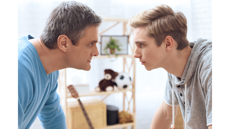 Father and son standing face to face. Father and troubled teenager trying to intimidate each other.