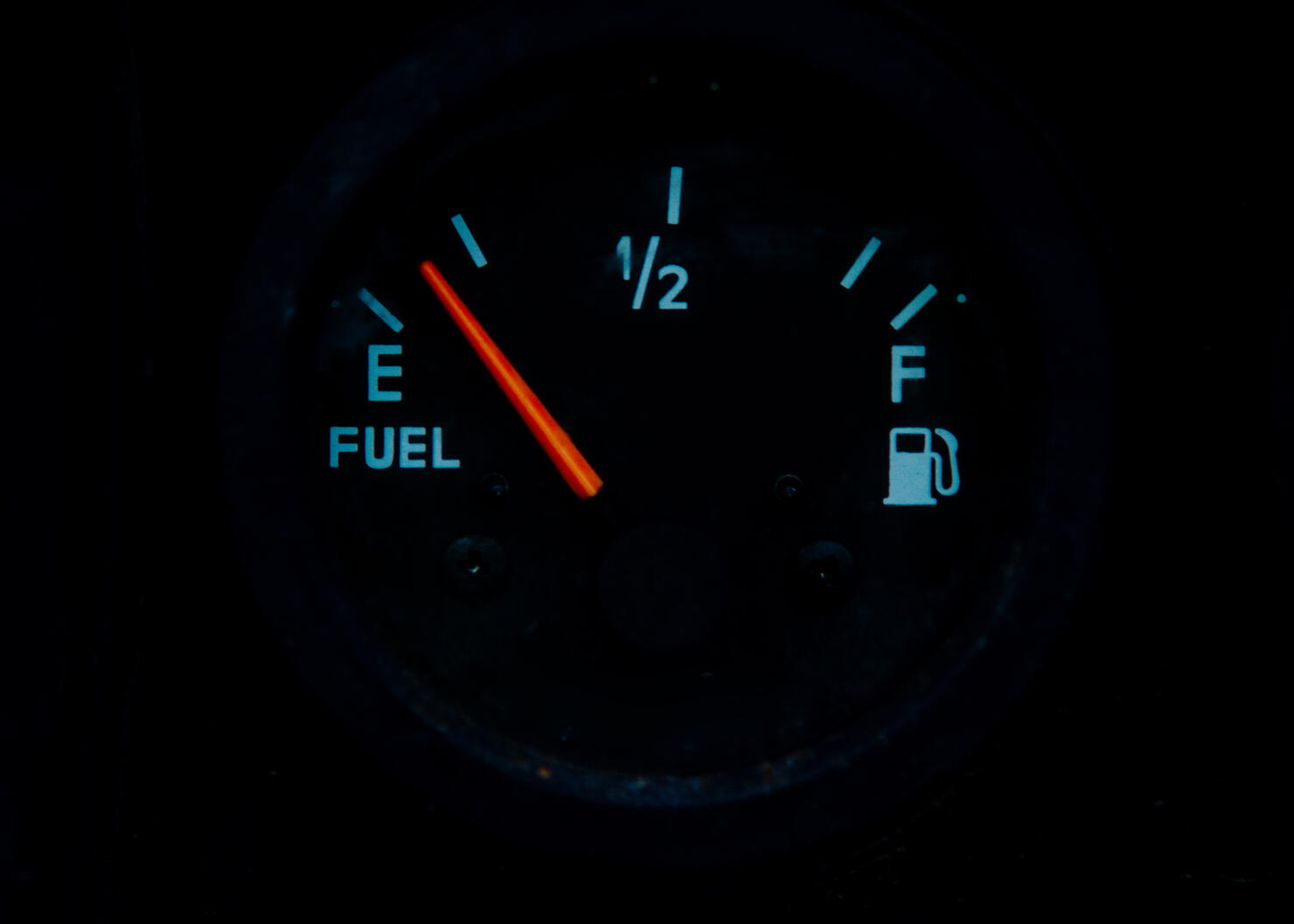 The fuel gauge on the black background showing that the tank is almost empty and it is a time to refuel