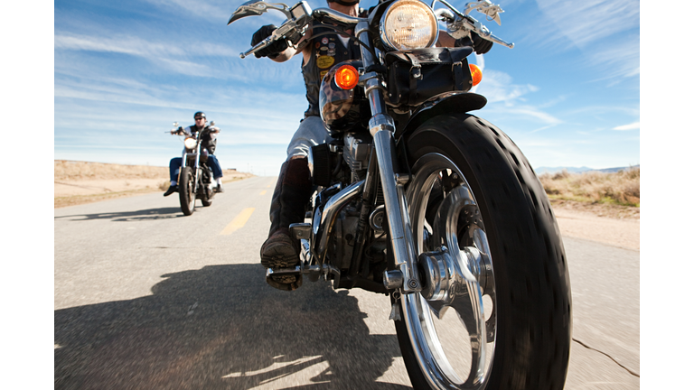 Two men riding motorcycles along road