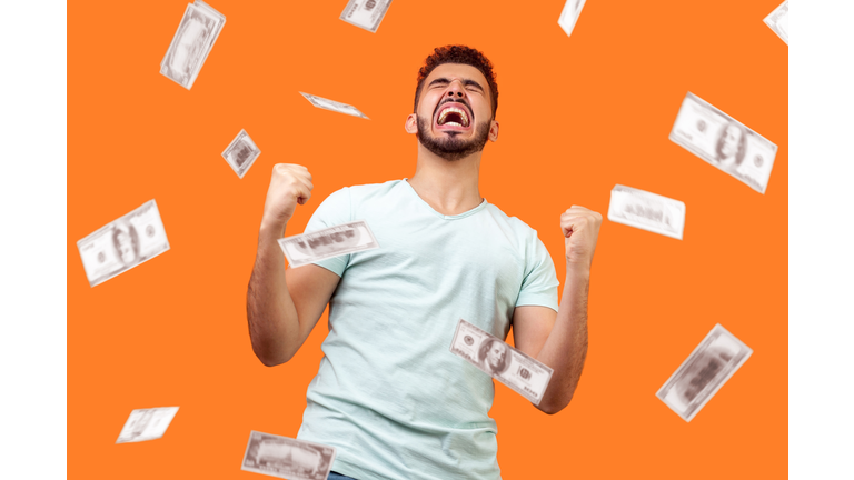 Money rain, winner and rich. Bottom view of ecstatic motivated man standing with raised fists and shouting for joy, winner excited for success. dollars falling.