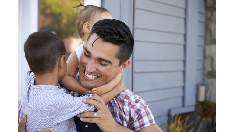 Father With Children Sitting On Steps Outside Home
