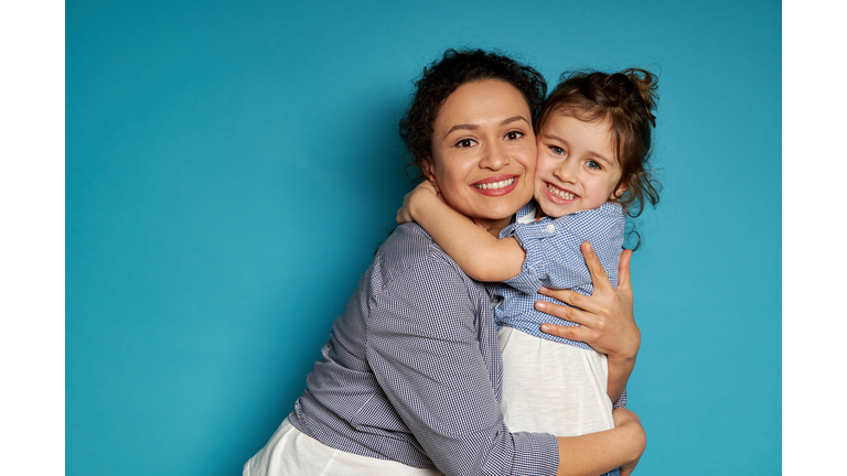 Cheerful mother hugging her daughter. Blue background, happy mother's day concept, Children protection day