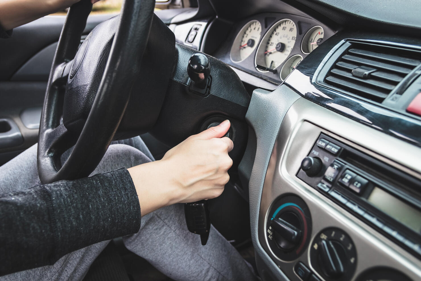 The girl starts the car by inserting the ignition key into the lock.