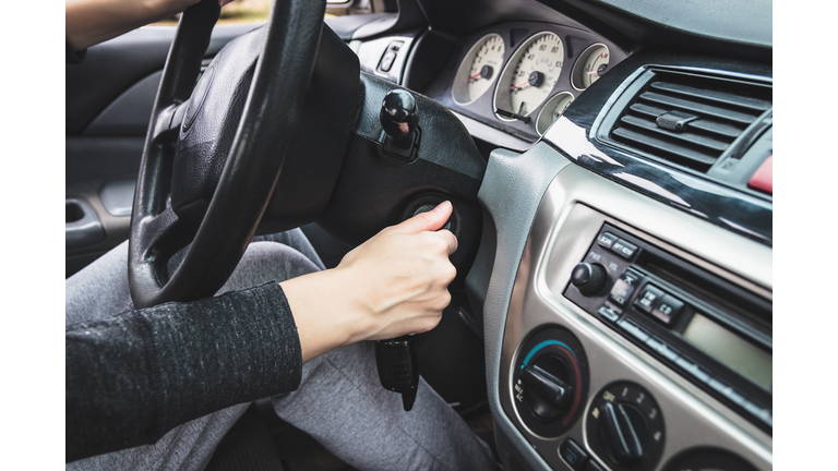 The girl starts the car by inserting the ignition key into the lock.