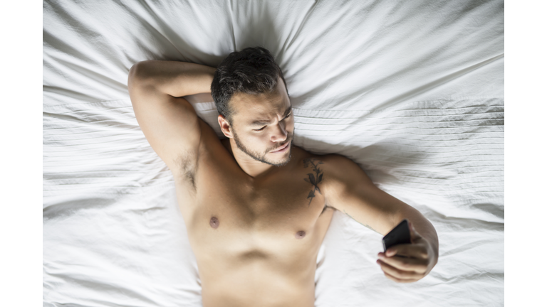 A young mexican man shirtless in white bed