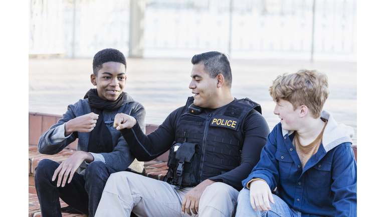Police officer in community, sitting with two youths