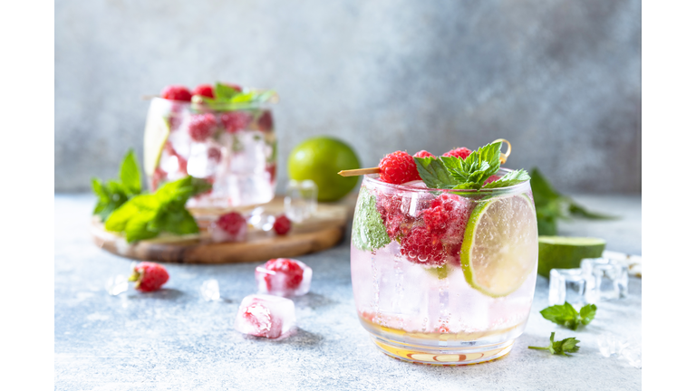 Hard seltzer cocktail with raspberries and lime on a gray stone table top. Copy space.
