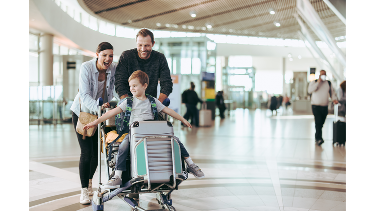 Couple pushing trolley with their child at airport