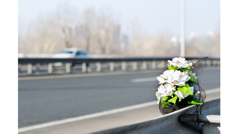 Artificial white roses flowers on the site of a traffic accident with a fatal outcome.