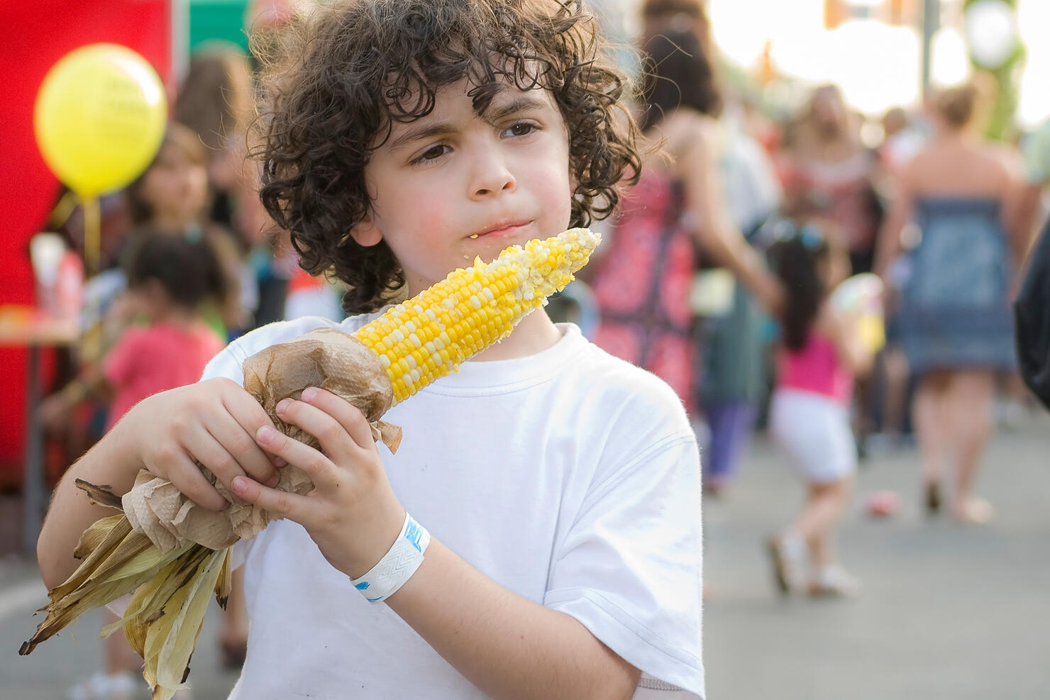 Child eating corn on the cob in a street festival