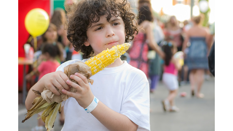 Child eating corn on the cob in a street festival