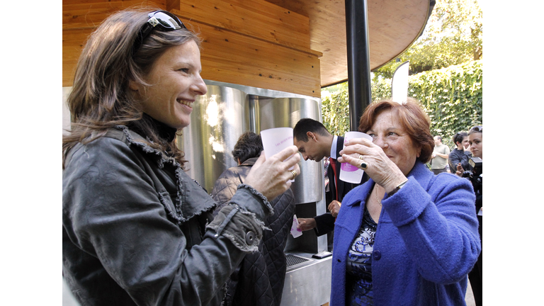Two women clink glasses in front of a so