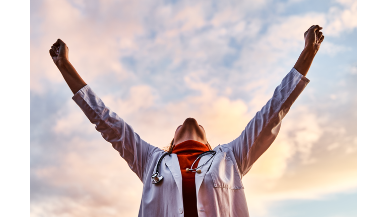 Female doctor raising her arms in victory. Concept of medicine and fight against coronavirus.