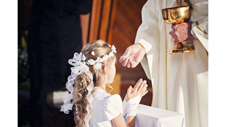 Communion and clergyman. First Holy Communion