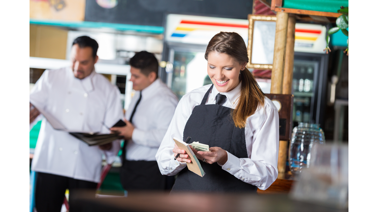 Friendly waitress in Tex-Mex restaurant counting tips after shift