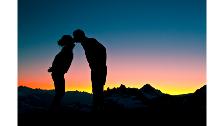 Silhouetted view of romantic couple kissing in the mountains at sunset