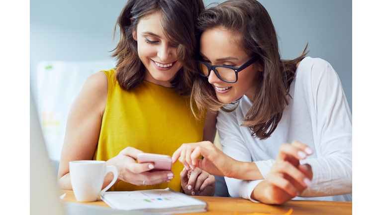 Female friends browsing internt on mobile phone