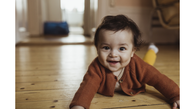 Portrait of smiling male toddler lying on floor at home