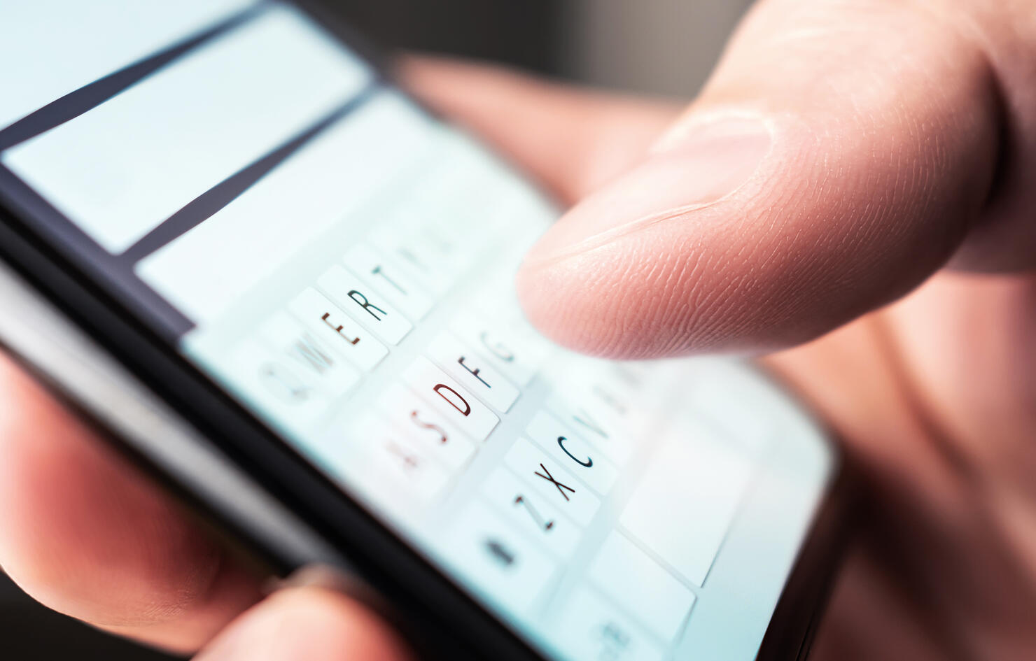 Text message with smartphone. Man texting sms with phone. Catfish or mobile scam. Digital instant messaging chat. Macro close up of keyboard and finger writing.