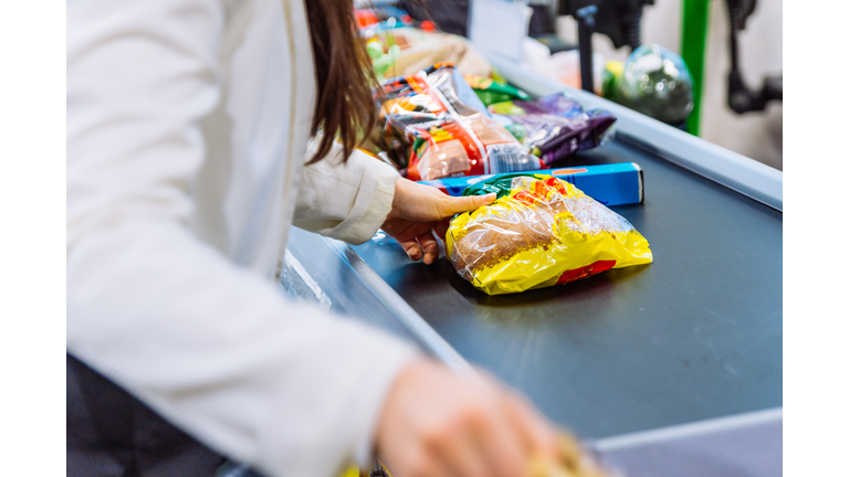 woman put products on the line near cashbox. grocery shopping concept