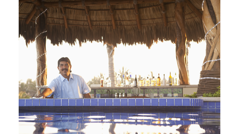 Hispanic bartender working near poolside