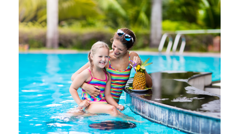 Mother and child drink juice in swimming pool