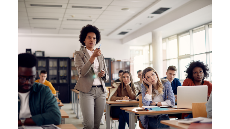 African American professor giving lecture to her student at university classroom.