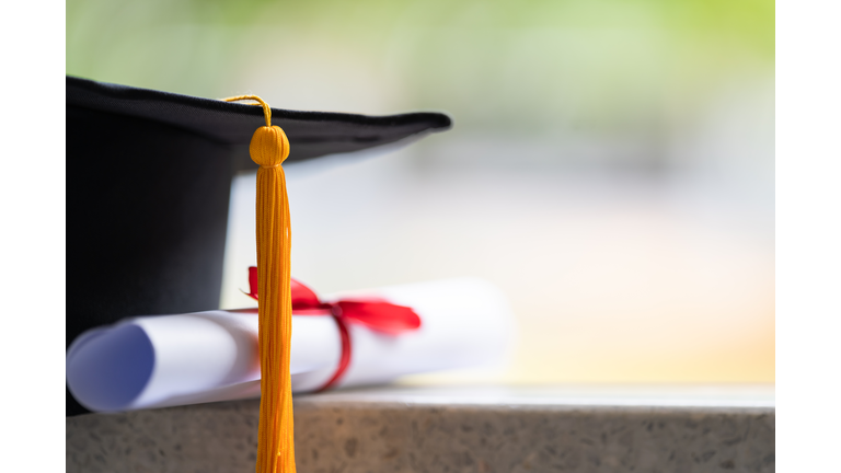 Close-up of a mortarboard and degree certificate put on the table. Education stock photo