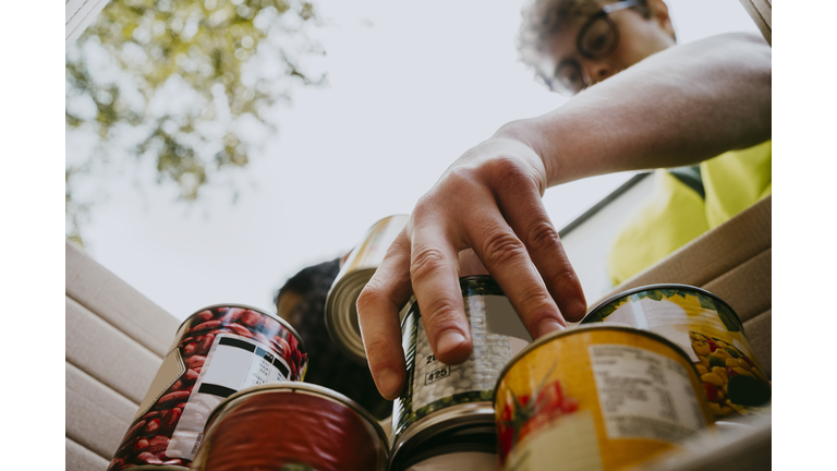 Young man holding canned food in box