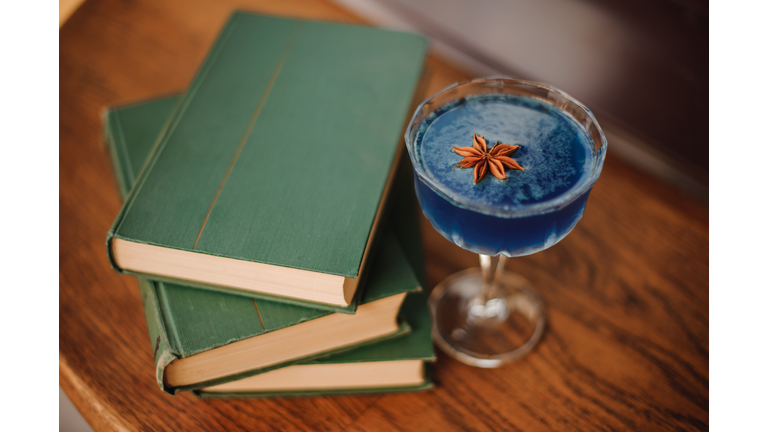 Blue cocktail on bar next to books