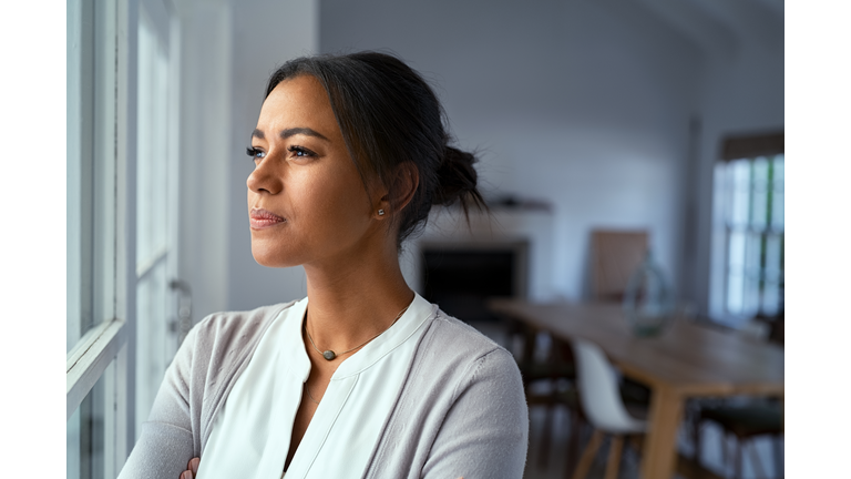 Thoughtful black woman looking outside window