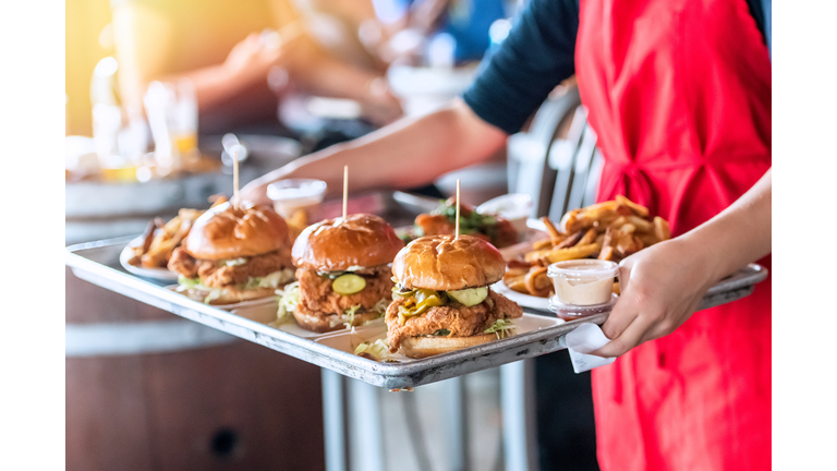 Waitress carrying a tray of fried chicken sandwiches and French fries