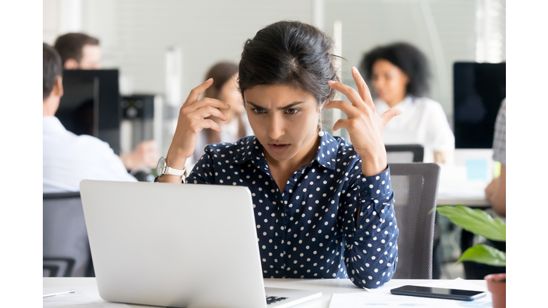 Upset female office worker reading unpleasant message