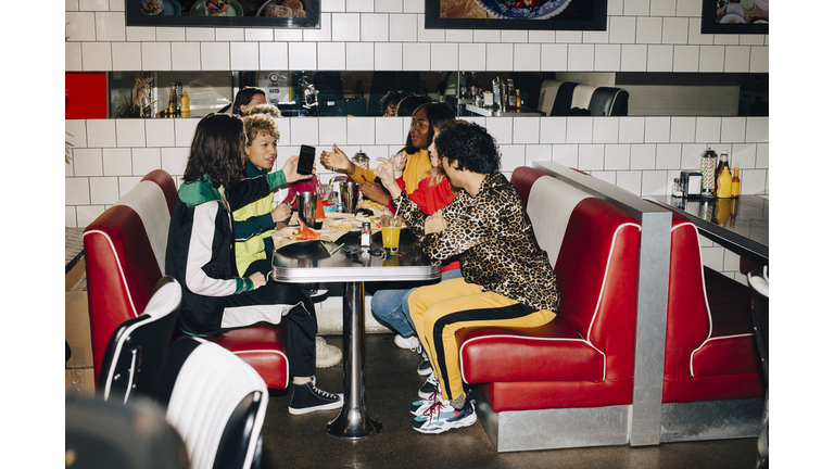 Side view of male and female friends talking at table in cafe