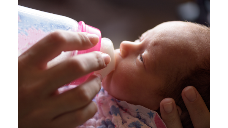 Mother feeds the newborn with bottle milk