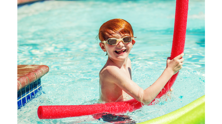 Young boy (6-7) playing in swimming pool