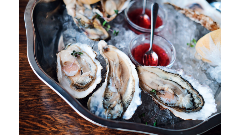 Oysters are on a plate with ice and sauce