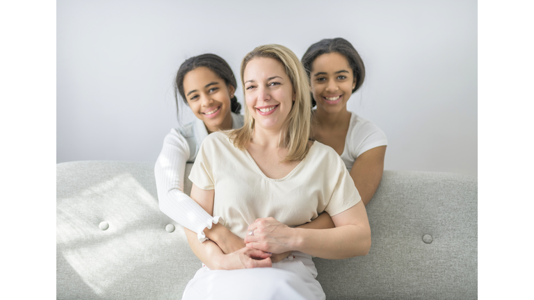 Adorable black twin teen with mother sit on sofa at home