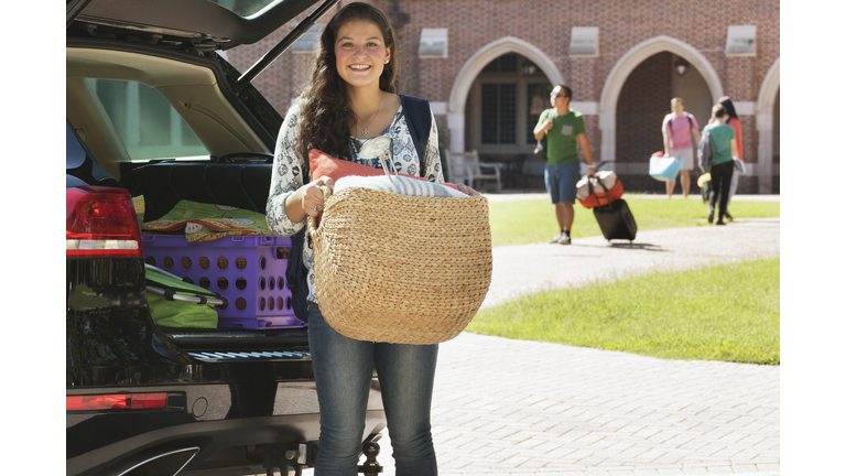 Teenage girl unloading car at college dormitory