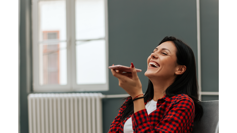 Woman laughing while talking on speakerphone.