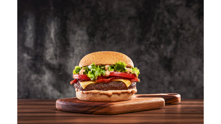 Cheeseburger with tomato and lettuce on wooden board