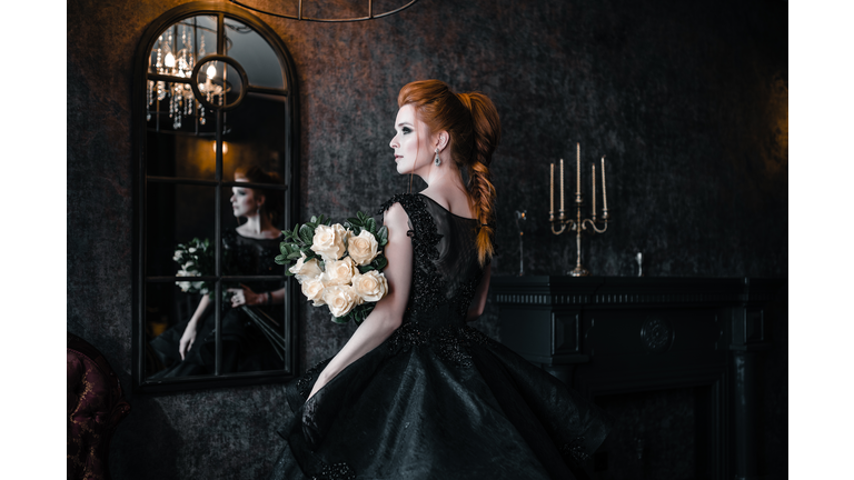 Attractive woman in black dress in medieval interior