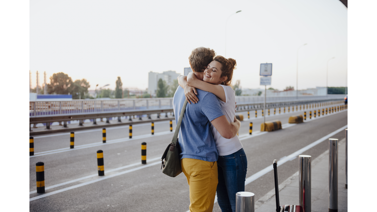 Happy girl hugging boyfriend after arrival from trip stock photo