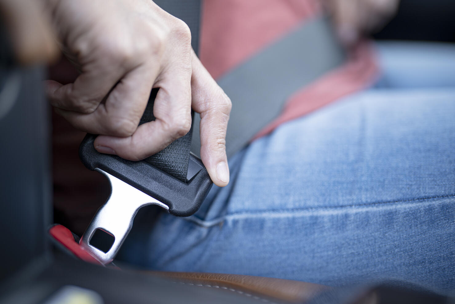 Car safety concept; Close up of hand woman pulling seat belt in her car.