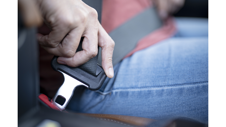 Car safety concept; Close up of hand woman pulling seat belt in her car.