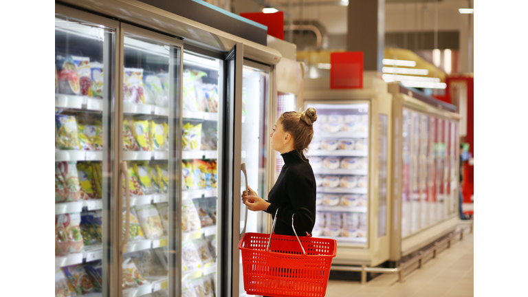 Woman choosing frozen food from a supermarket freezer
