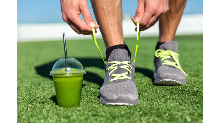 Green smoothie fitness man tying running shoes